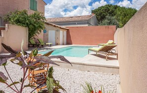 A pool area with lounge chairs, a small garden with plants, and a building with a tiled roof. - Gorgeous home in Creissan with WiFi (Creissan)