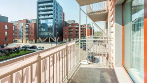 A balcony with a view of modern buildings, a parking area, and a clear sky. - Apartinfo Apartments Waterlane Island (Gdansk)