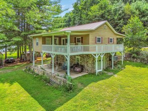 A two-story house with a balcony, stone foundation, and a well-maintained lawn. - Roxy's Riverfront Playhouse on the New River - Fire Pit (Crumpler)