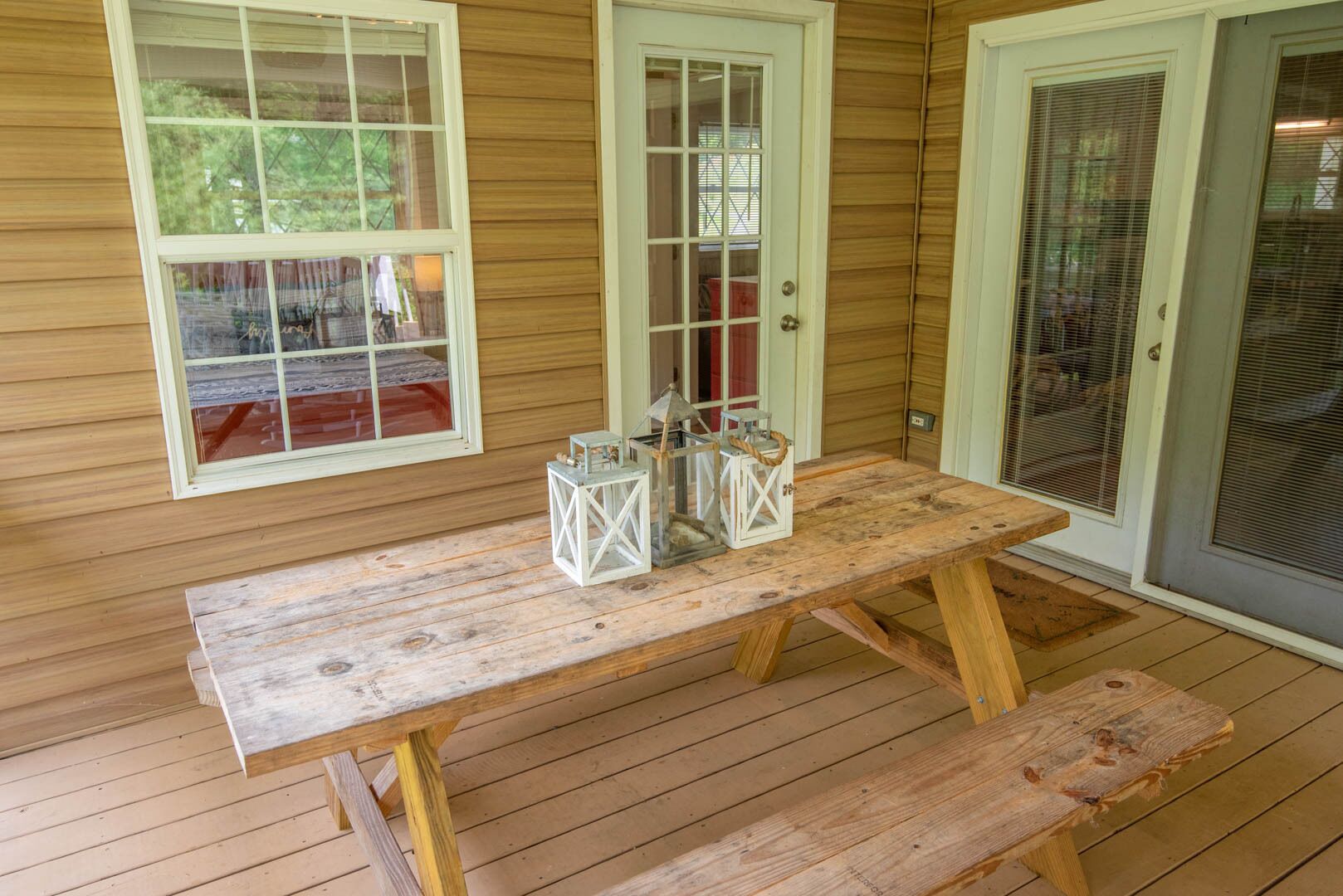 A wooden deck with a picnic table and lanterns.