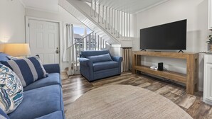 Ett vardagsrum med en trappa, en soffa, en tv på ett träställ och en lampa.