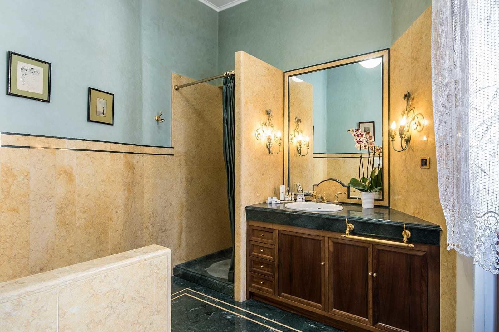 Un baño con piso de mármol, lavamanos con tocador y ducha con cortina.