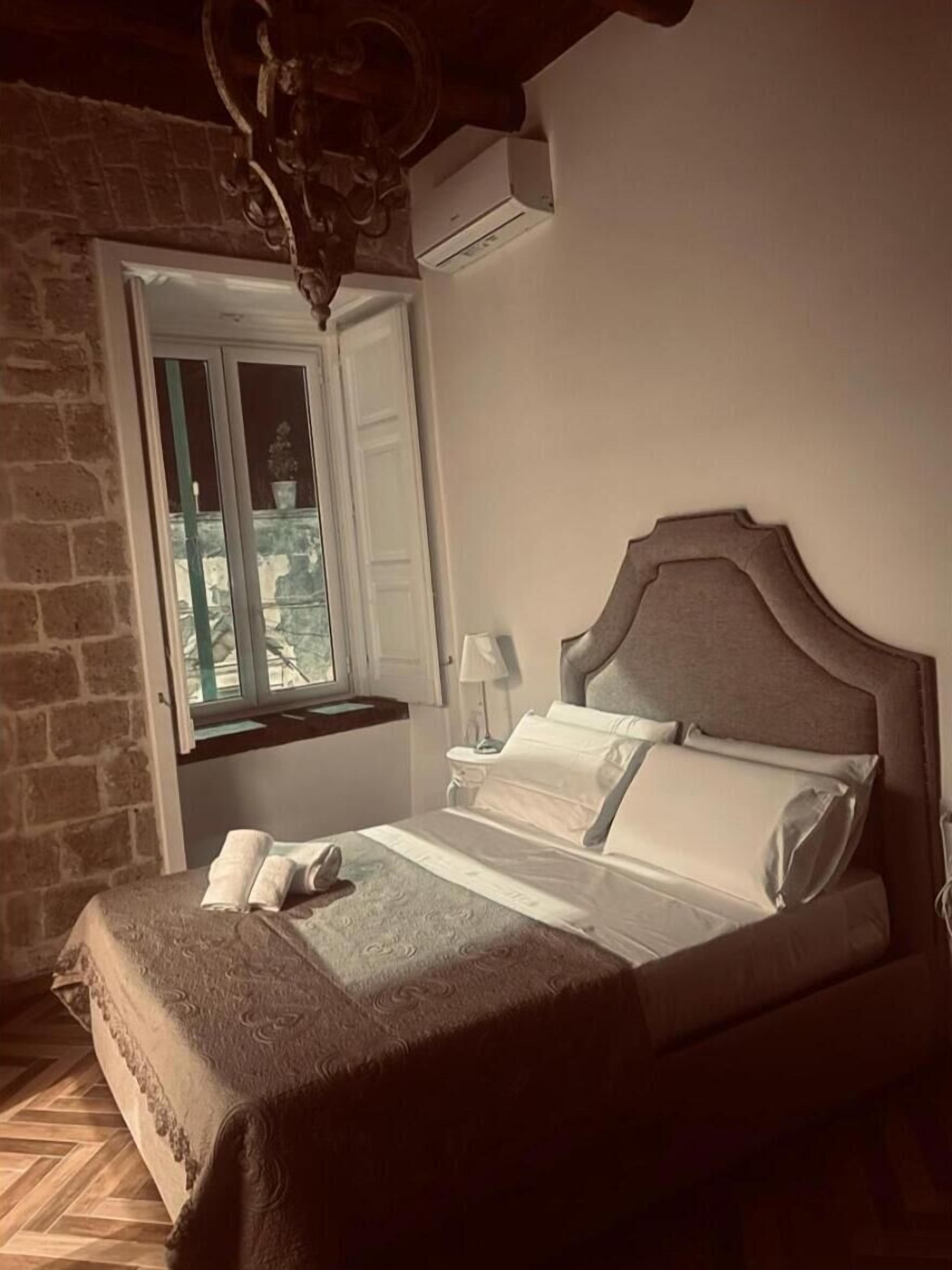 Ein Schlafzimmer mit Bett, Fenster mit Blick, einer Lampe und einer Klimaanlage.