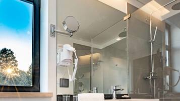 A modern bathroom with a large mirror, a hairdryer, a shower, and a sink.