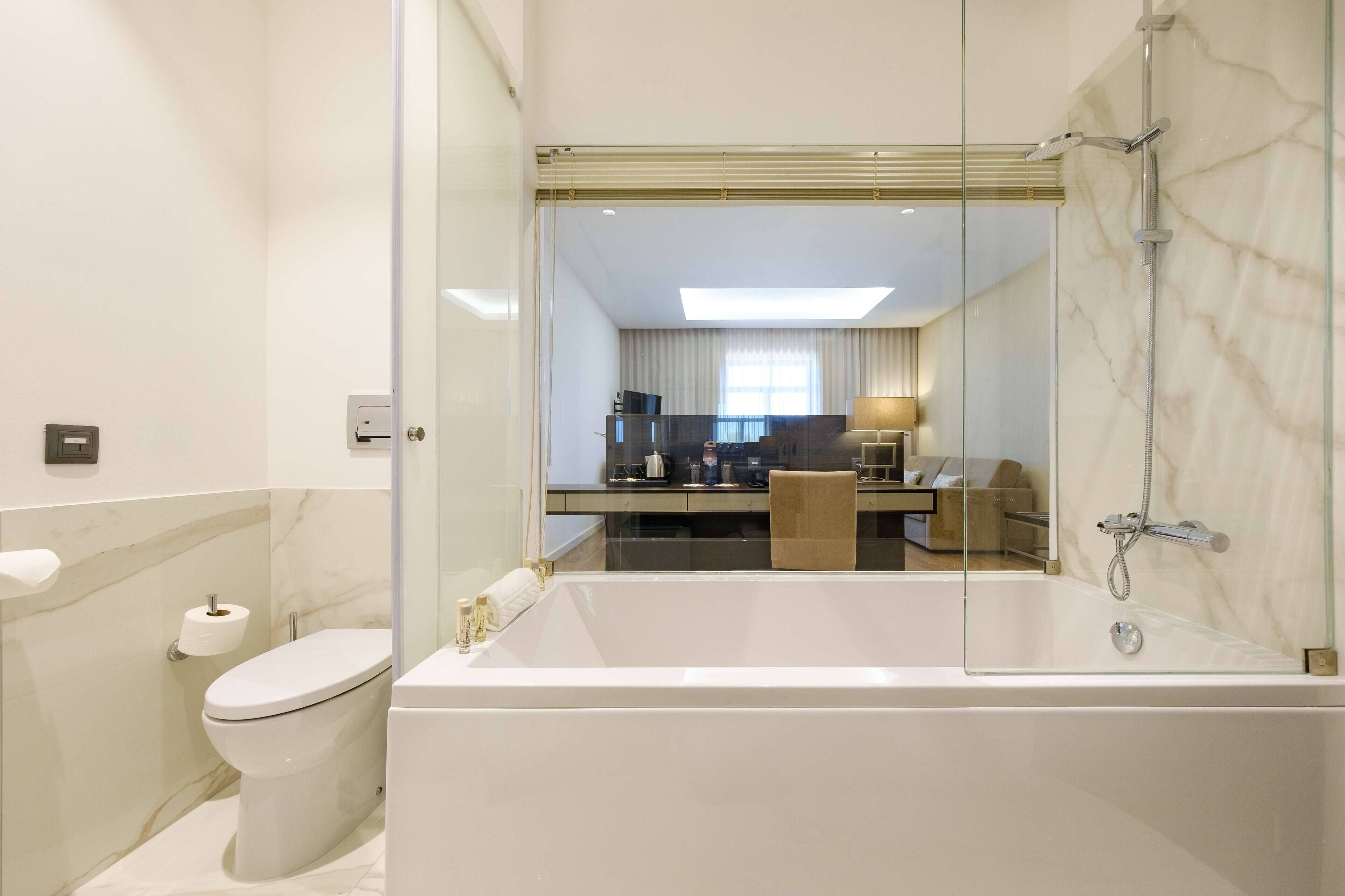 A modern bathroom with a large bathtub, toilet, and a glass-enclosed shower area.
