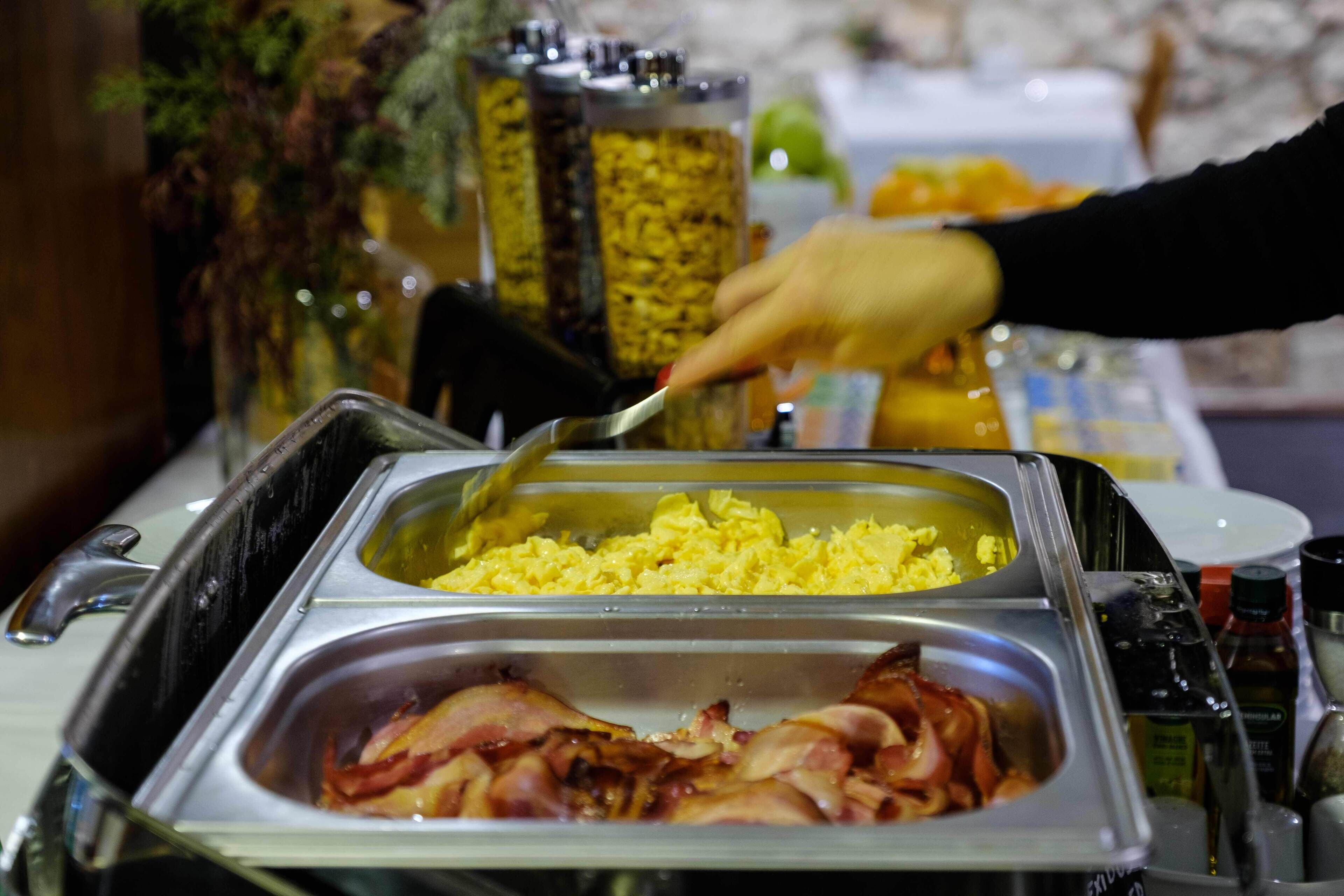 Un bufé con huevos revueltos y tocino.
