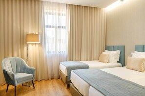 Une chambre d’hôtel avec deux lits, une chaise et une lampe.