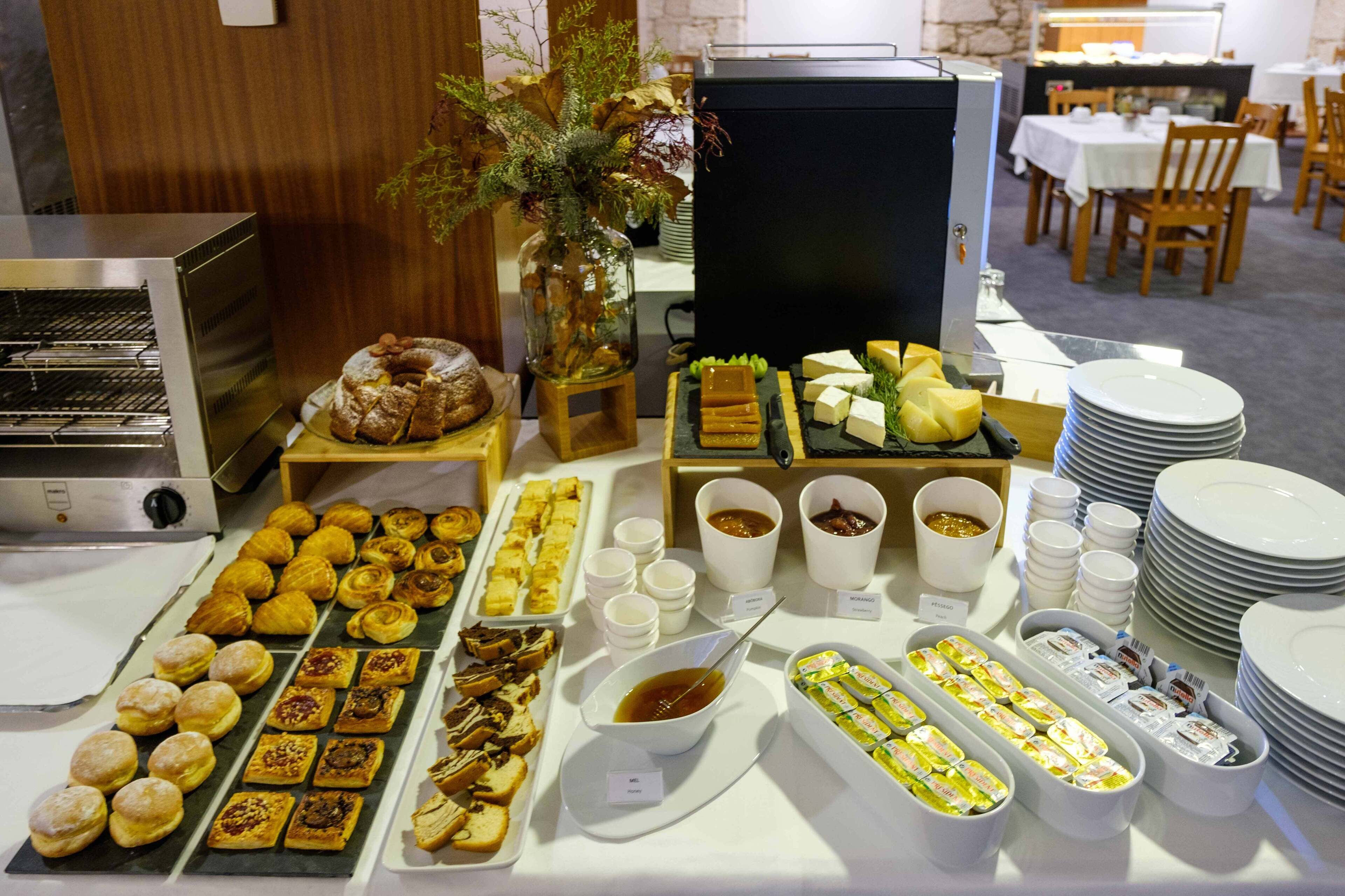 A buffet with various pastries, cheeses, and condiments.