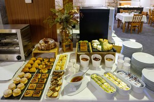 A buffet with various pastries, cheeses, and condiments.