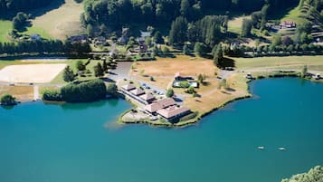 Vista aérea de una propiedad junto al lago con un amplio campo abierto, una pequeña isla con edificios y un muelle.
