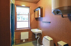 Un baño con ventana, lavamanos, inodoro y toallero.