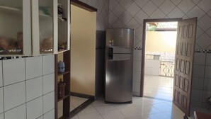 Een keuken met een koelkast, een kast met glazen deuren en een betegelde vloer.