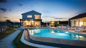 A modern house with a swimming pool, lounge chairs, and a covered patio area. - Lovely home in Marcana with sauna (Marcana)