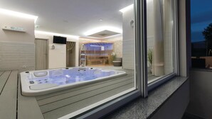 A spa area with a hot tub, wooden shelving, and a television on the wall. - Lovely home in Marcana with sauna (Marcana)