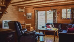 A cozy cabin interior with a wooden interior, a leather sofa, a dining table, and a view of a lake through large windows. - 2 bedroom gorgeous home in ølensvåg (Ølensvåg)