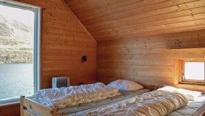 A wooden cabin room with a bed, a window, and a view of a lake. - 2 bedroom gorgeous home in ølensvåg (Ølensvåg)