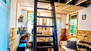Una habitación estilo loft con techo de madera, una escalera, una mesa de comedor y un sofá.