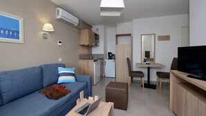 A modern living room with a sofa, a coffee table, a TV, and a dining area with a table and chairs.