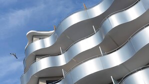 A modern building with curved balconies and a clear sky.