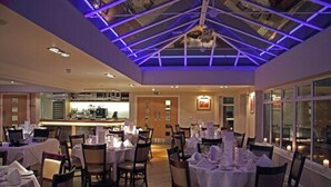 A restaurant with tables set for dining, a bar area, and a view through large windows. - Little Downham Anchor (Ely)