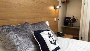 A bed with a grey textured pillow and a navy pillow with a white anchor design. - Little Downham Anchor (Ely)