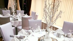 A round table set with white tablecloths, silverware, and glassware, surrounded by white chairs. - Little Downham Anchor (Ely)