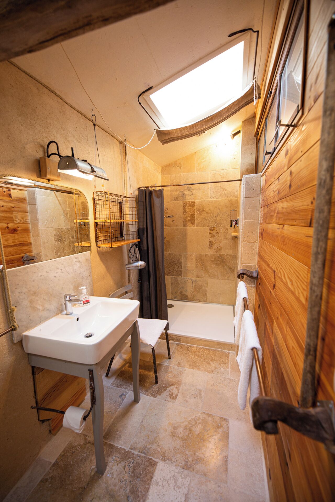 A compact bathroom with a shower, a sink, and a small window.