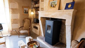 Ein rustikales Wohnzimmer mit sichtbaren Holzbalken, einem Kamin und einem Fernseher.