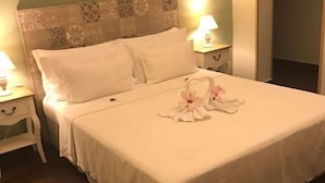A neatly made bed with white linens and a decorative swan and flowers on the bedspread. - Guest House Le Ginestre Dell'Etna (Belpasso)