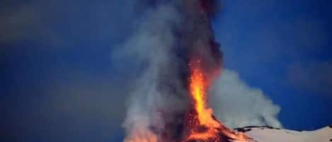 A volcanic eruption with lava flowing down a snowy mountain.