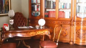 A room with a wooden desk, two chairs, a bookshelf, and a framed painting on the wall. - Guest House Le Ginestre Dell'Etna (Belpasso)