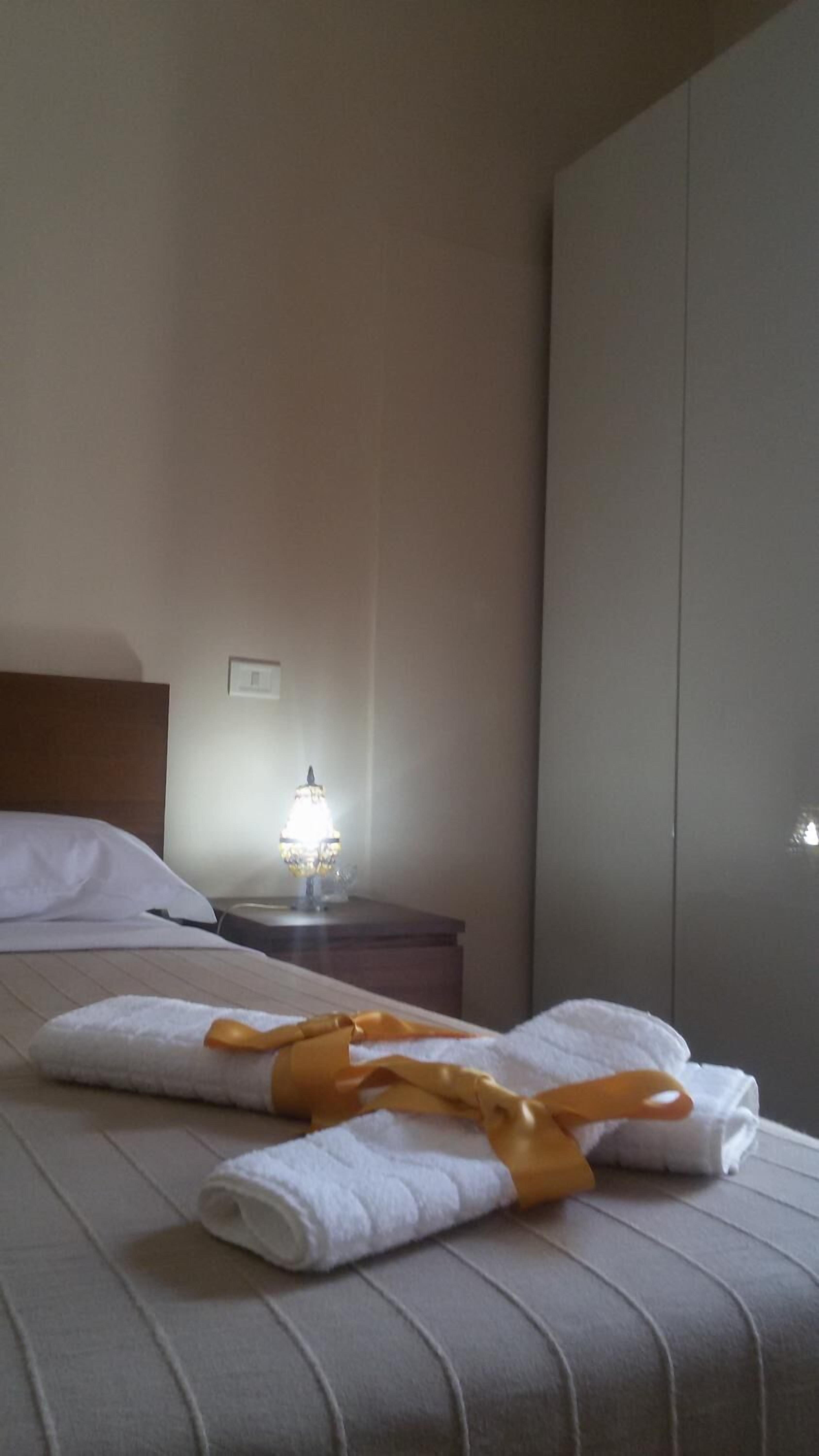 Un lit bien fait, avec du linge de lit blanc et une serviette jaune nouée en forme de ruban.