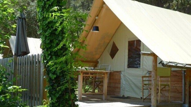 A tent with a wooden deck, a table, and chairs. - Amazone (Auxonne)