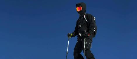 A person skiing on a snowy slope with a clear blue sky.