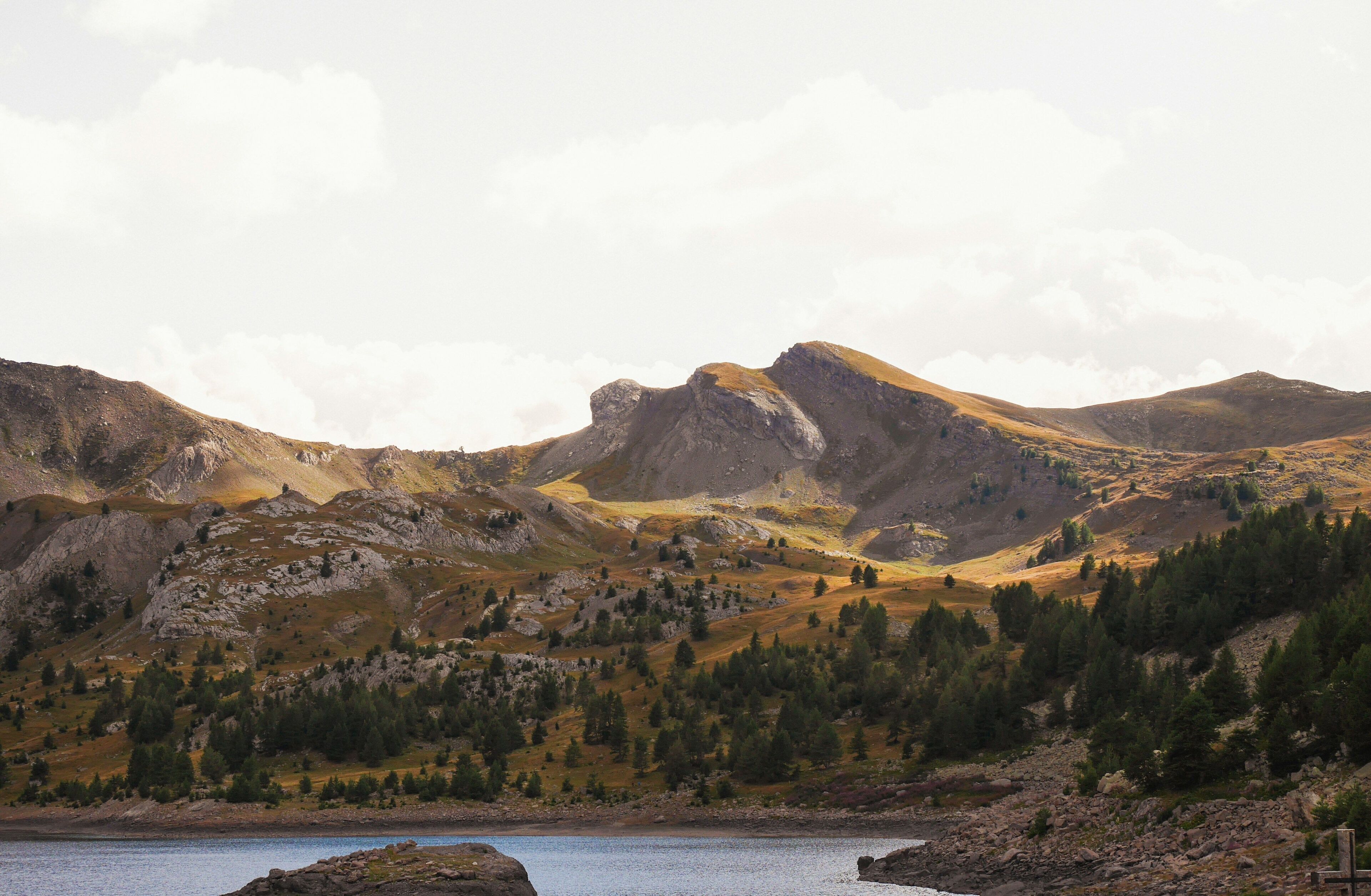 Un paysage montagneux avec un lac et des collines boisées.