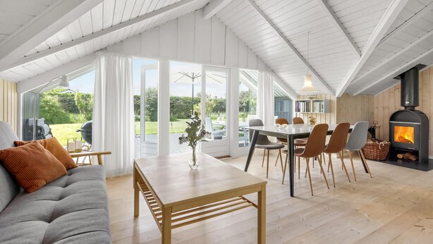 Een ruime woonkamer met een hoge plafond, een eettafel met stoelen, een bank en een open haard.