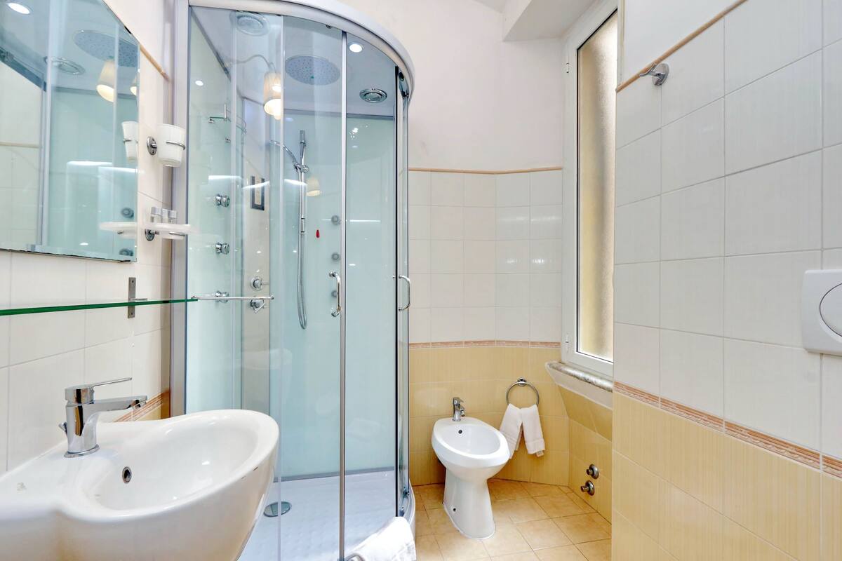 A modern bathroom with a glass-enclosed shower, a sink, and a bidet.