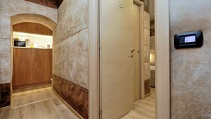 A hotel room with a wooden wardrobe, a beige door, and a wall-mounted control panel. - Gialli Vatican Guesthouse (Rome)