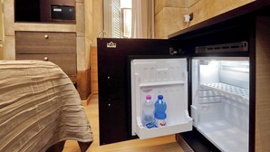 A hotel room with a bed, a built-in wardrobe, and a refrigerator with two bottles of water. - Gialli Vatican Guesthouse (Rome)