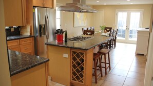 A kitchen with wooden cabinets, a stainless steel refrigerator, a built-in stove, and a wine rack. - Well-Furnished Oceanside Home! (Pismo Beach)