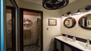A bathroom with a vanity, a round mirror, and a ceiling fan.