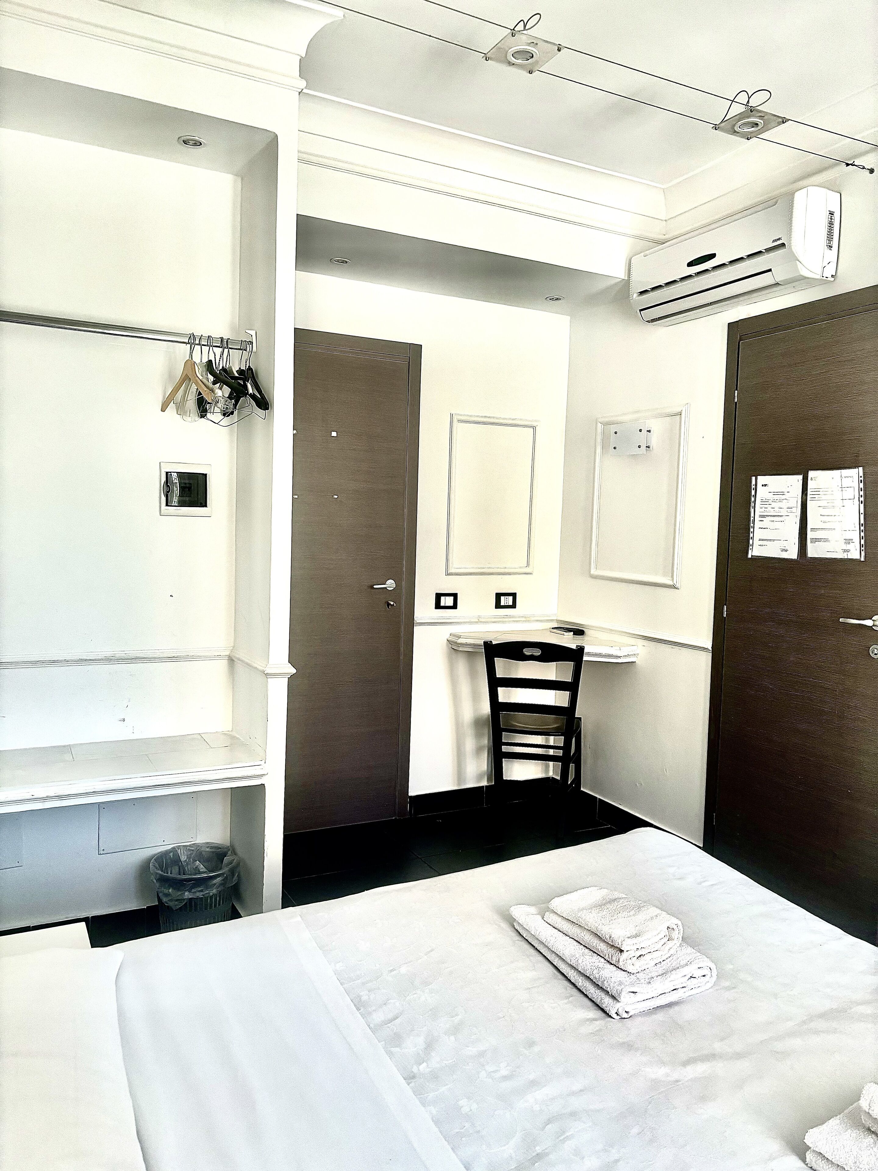 A hotel room with a bed, a chair, a desk, and a wardrobe.