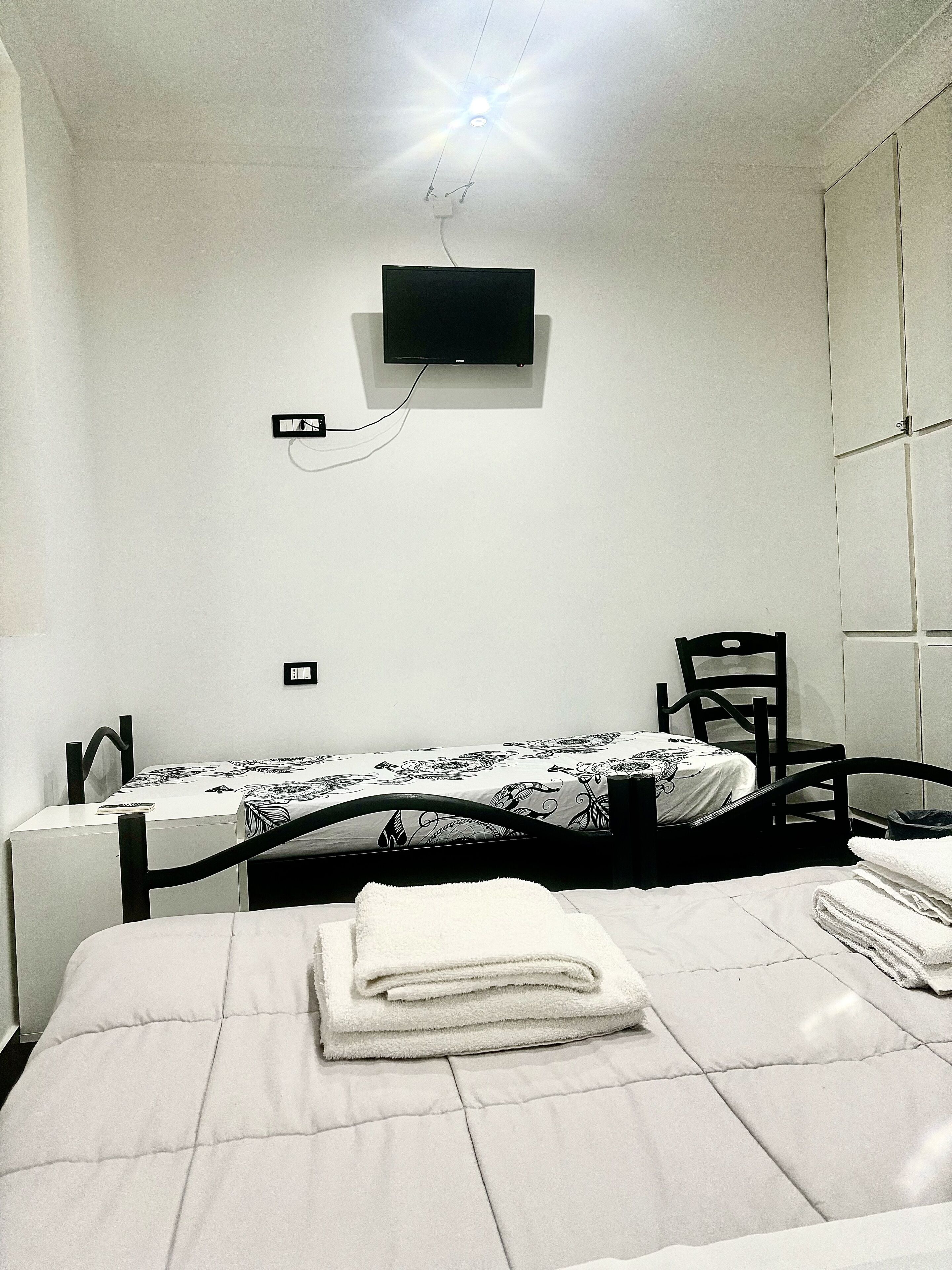 Een slaapkamer met een bed, een bureau, een stoel en een televisie aan de muur.