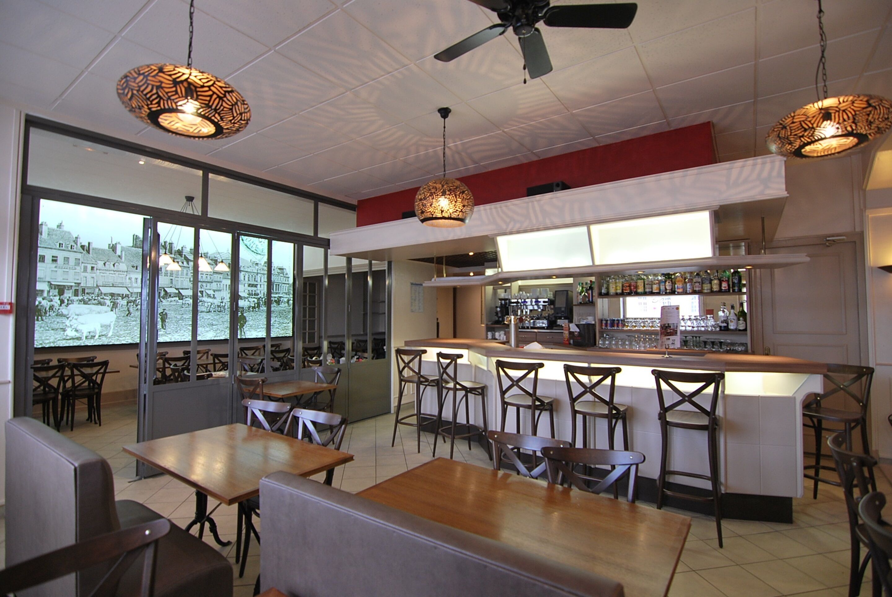 A restaurant with a bar area, high chairs, and a view of a cityscape through large windows.
