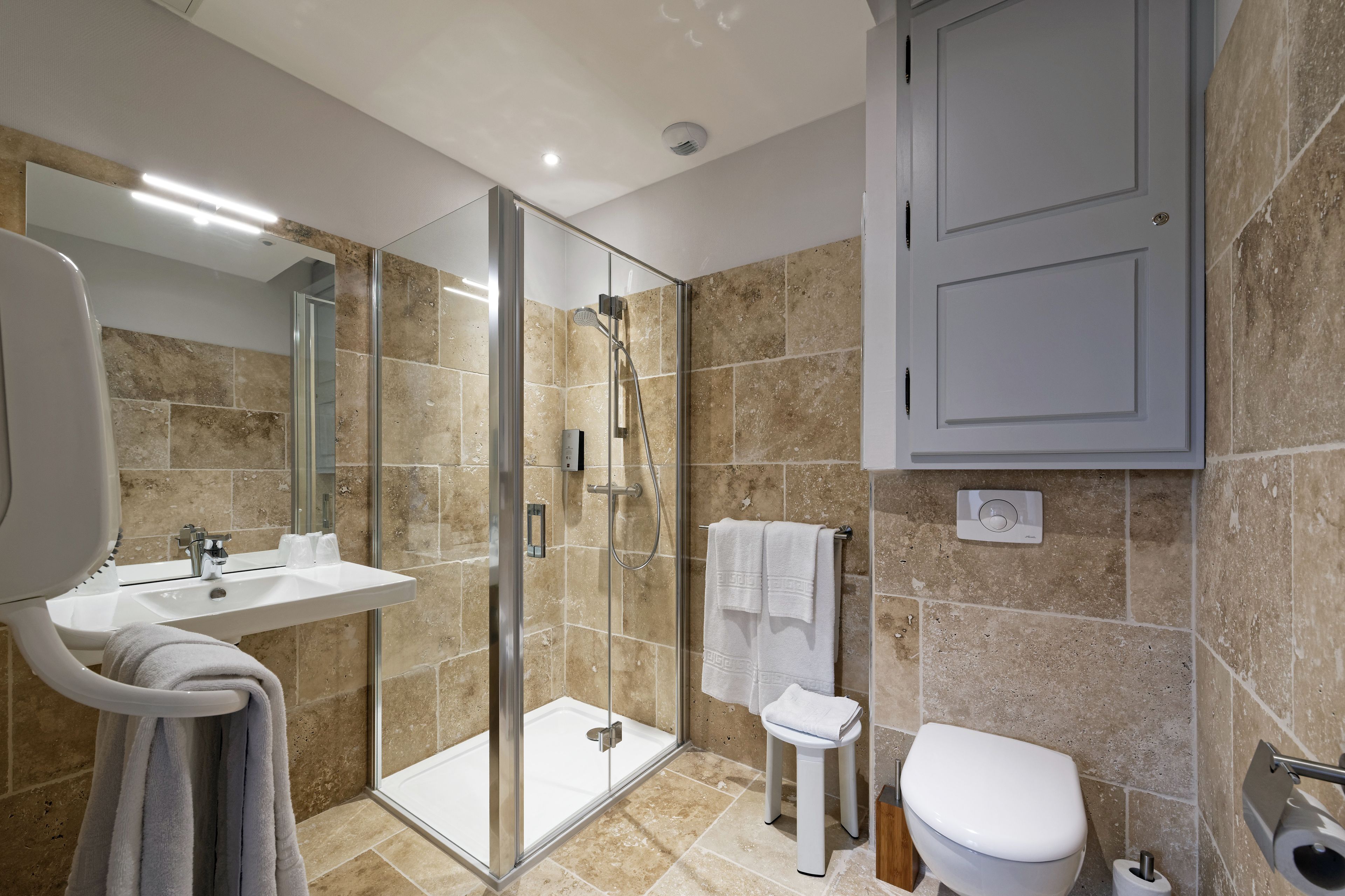 A modern bathroom with a glass-enclosed shower, a white sink, and a toilet.