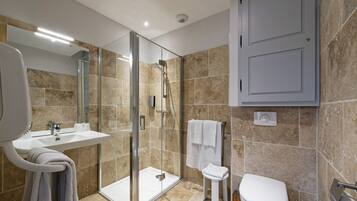 A modern bathroom with a glass-enclosed shower, a white sink, and a toilet.