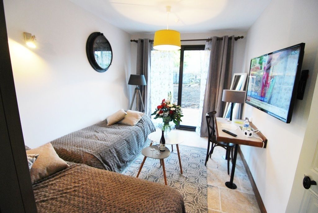 A hotel room with two beds, a desk with a lamp, a TV, and a window with curtains.