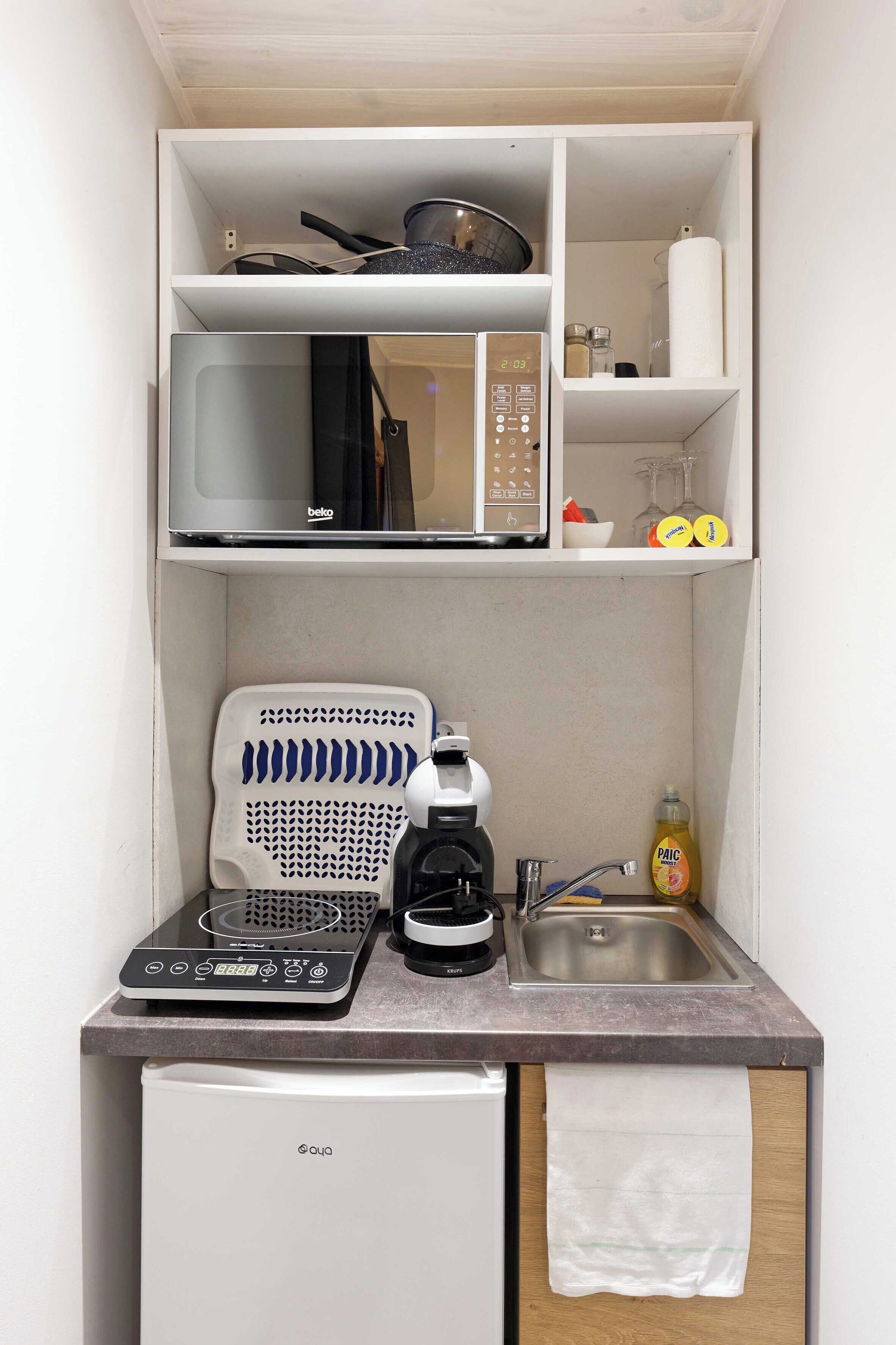 Eine kleine Küchenzeile mit Mikrowelle, Kaffeemaschine und kleinem Kühlschrank.
