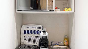 Eine kleine Küchenzeile mit Mikrowelle, Kaffeemaschine und kleinem Kühlschrank.