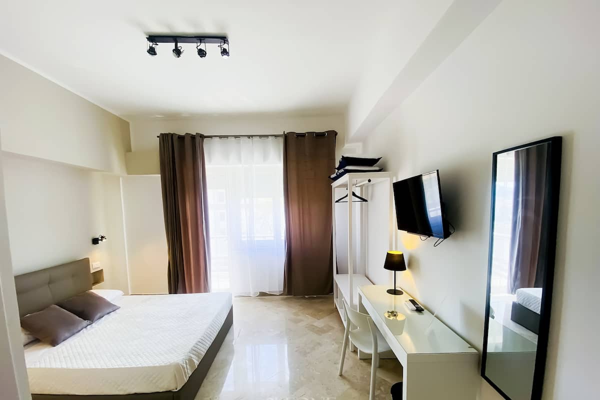 A hotel room with a bed, a desk, a TV, and a mirror.